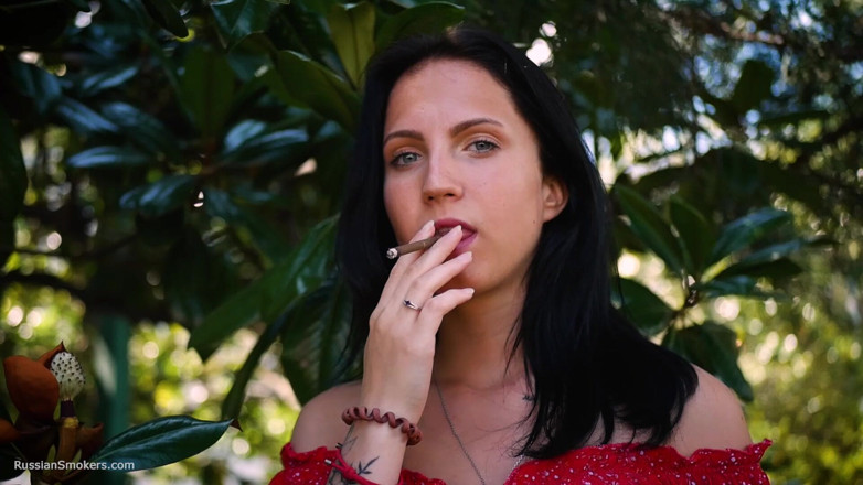 Russian Smokers: Sinnliche brünette im roten kleid, raucht gerollte zigarette