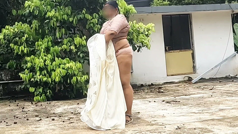 Anne Ipe: 一个穿着白色裙子和粉色上衣的丰满女人脱光衣服，在户外裸体散步