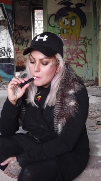 Blond dama pali elektronicznego papierosa na schodach