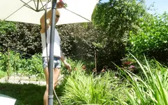 Alexa Cosmic la ragazza trans bagna e wetlook in giardino con t-shirt bianca e pantaloncini di jeans sott'acqua...