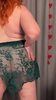 Une rousse mature de plus de 50 ans fait un strip-tease dans une robe émeraude transparente