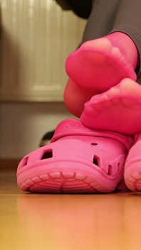 Retrait des chaussettes et jeu de chaussures de sabot sous le bureau - legging gris, sabots roses et bas nylon
