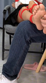 La ragazza scalza è legata con corde rosse, le solletica i piedi e ha il suo feticismo per i piedi