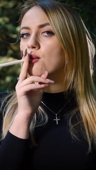 Gagică blondă sexy care fumează o țigară neagră în natură