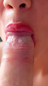 Her lips gently caress the large cock until her mouth fills with cum, close-up
