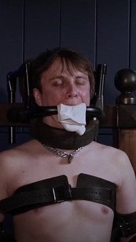 Ricky su una sedia da bondage, bavaglio d'acciaio e imbottiture per calzini.