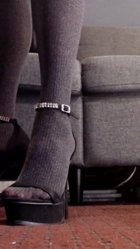 Strap-on hitam pakai sepatu hak tinggi dan stoking tembus pandang