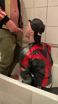穿着皮夹克的大男人撒尿在皮衣摩托骑自行车的人身上