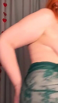 穿着透明翡翠连衣裙的红发熟女50+脱衣舞