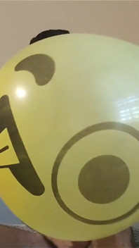 Mamando un enorme globo sonriente mientras se masturba