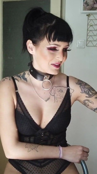 Señora gótica tatuada fumando en la cocina