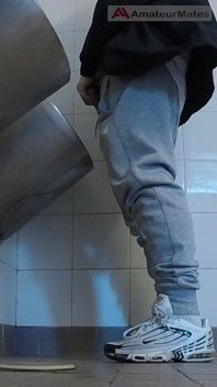 Amateurjongens in sportschoenen trekken af en proberen af te trekken in het urinoir van openbare toiletten
