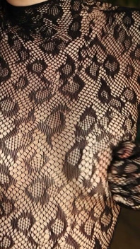Estoy posando en un traje de rejilla negro y tacones, complacándome con mis dedos