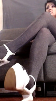 Gambe incrociate con le calze ed i tacchi stipper bianchi e scarpe