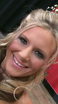 Une blonde à forte poitrine dans un string noir avec un jouet en verre