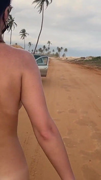 Femme nue à forte poitrine marchant sur la route à côté de la voiture