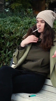 Joven morena está dando un paseo sin prisas con cigarrillo allwhite de 120 mm