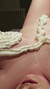 En naken kvinna med stora tuttar i en massagesalong med vispad grädde.
