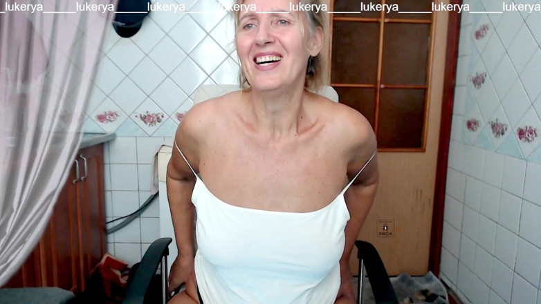 Lukerya: Lukerya veselă în bucătărie în pantaloni scurți albi și un tricou