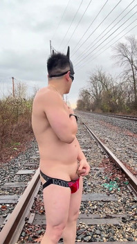 Dios muscular asiático empapado por la lluvia en Jockstrap rebota pecas, muestra v-taper y come su carga masiva en las vías del tren