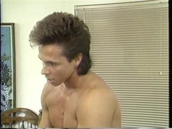 The hung stud sits on the edge of the bed while getting his cock serviced