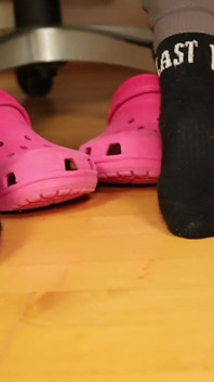 Onder bureau voetspel - roze klompen en versleten sokken