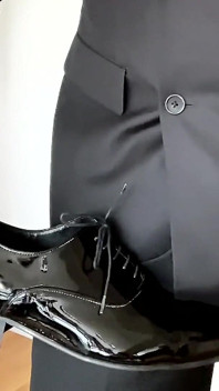 Homem de terno se masturba em sapatos de couro envernizado