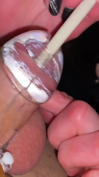 Une MILF joue avec une bite dans une cage de chasteté plastique