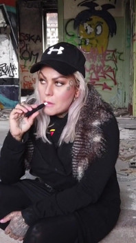Loira fuma um cigarro eletrônico na escada