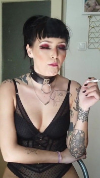 Signora gotica tatuata che fuma in cucina