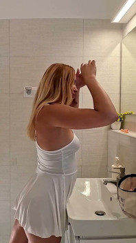 Hermosa profesora de yoga caliente rubia en un mini vestido medio transparente se desnuda en el baño