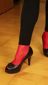 Peeptoe dangling w czerwonych pończochach i czarnych leginsach