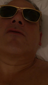 En primer plano - masturbación desnuda en la cama con gafas de sol y bosteando