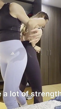 체육관 옷을 입고 여자 팔과 엉덩이 레슬링 경기를 하는 두 명의 여성.