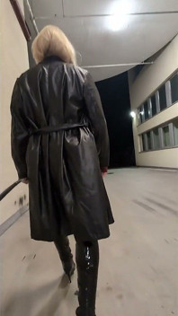 Promenade dans une maison de parking, une blonde dans des bottes overknee, robe en pvc rouge et long manteau de cuir