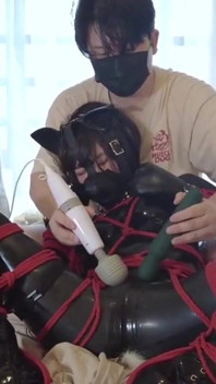 Einen latexanzug tragen und an einem roten Seil gefesselt
