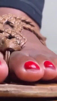 茶色のサンダルを履いたエボニーの足がからかう
