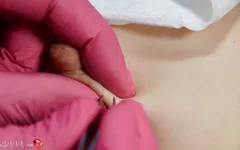 Esteticista despoja de pelo en los pezones de niña en depilación y masajea tetas en guantes de látex rojos