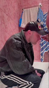 Un gopnik russe en veste en cuir et chaussures de sport prend un jet d’urine d’un homme puissant