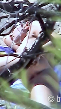 セクシーなヌーディストのブルネットがビーチでトップレス