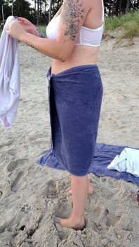 Em primeiro plano. Você assiste como uma modelo peituda, de sua presença, tira roupa na praia, banhos e brinca na areia.