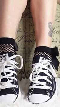 เท้าฉันเล็กน่ารักในรองเท้า Converse โดยเฉพาะกับถุงเท้าลูกไม้ข้อเท้าที่มีโบว์ใหญ่ๆ