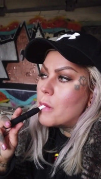 Blond dama pali elektronicznego papierosa na schodach