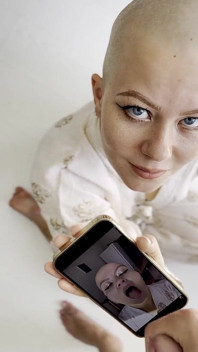 Cumtribute, une fille chauve nettoie son téléphone après