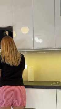 Chica universitaria sexy caliente en pantalones cortos y cortos para mostrar su culo desnudo y su apretado coño carnoso en la cocina