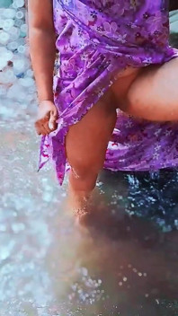 La donna culona nuota nuda nell'acqua e scopa nell'acqua su un fiume all'aperto