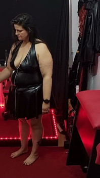 Dominatrix de látex con curvas sujeta y dilata esclavo enmascarado