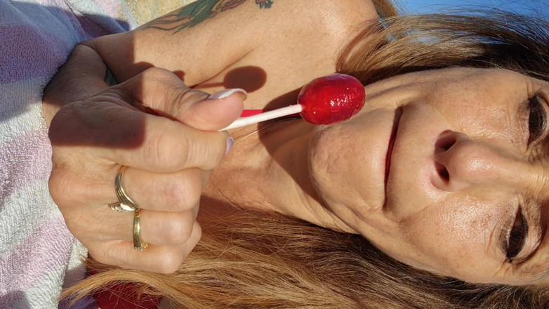 Melissa Johnson: Melissa Johnson suger och slickar en cherry lollipop på stranden