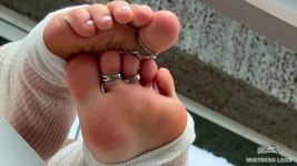 Le dita dei piedi bianche in nylon gaie bianche ti provocano sul balcone estivo