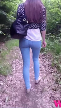 Si rambut coklat terdesak dengan kaki panjang dalam seluar jeans ketat berjalan di hutan palung mencari tempat untuk ke Kencing